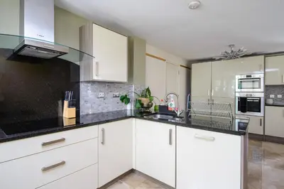 a kitchen with white cabinets and black counter tops at Deluxe 2 3 Bed HotTub SkyTV in Saffron Walden