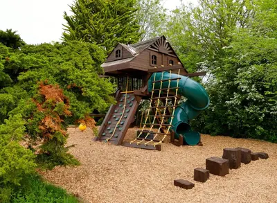 a playground with a house and a slide at Deluxe 2 3 Bed HotTub SkyTV in Saffron Walden
