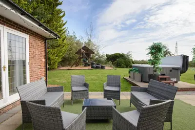 a patio with chairs and a table and a grill at Deluxe 1 Bed Versace HotTub SkyTV in Saffron Walden