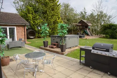 a patio with a grill and a table and chairs at Deluxe 1 Bed Versace HotTub SkyTV in Saffron Walden