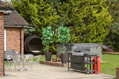 a patio with a grill and a table and chairs at Deluxe 1 Bed Versace HotTub SkyTV in Saffron Walden
