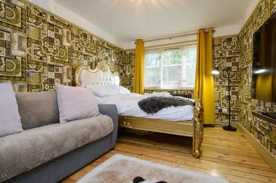 a bedroom with a bed and a couch at Deluxe 1 Bed Versace HotTub SkyTV in Saffron Walden
