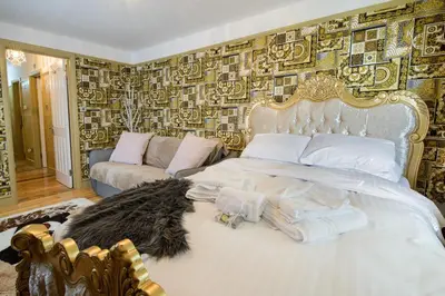 a bedroom with a bed and a couch in it at Deluxe 1 Bed Versace HotTub SkyTV in Saffron Walden