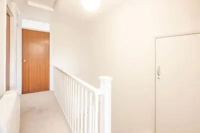 a white hallway with a wooden door and stairs at 111 Front Street, Orford in Woodbridge