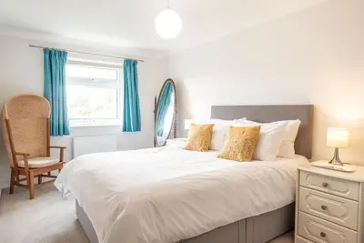 a bedroom with a large white bed with blue curtains at 111 Front Street, Orford in Woodbridge