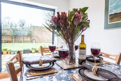 a table with glasses of wine and a vase of flowers at 111 Front Street, Orford in Woodbridge