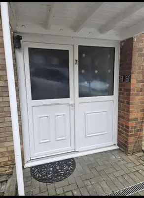 a white garage door with two windows on a house at Stylish Studio Stevenage in Stevenage