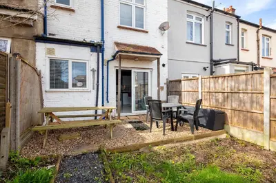 a backyard with a wooden fence and a table and chairs at Welcome to Northview House Stylish 4 Bedroom Home in Southend by Jesswood Properties Contractors Corporates Relocation Stays Long Stays Welcome in Southend-on-Sea