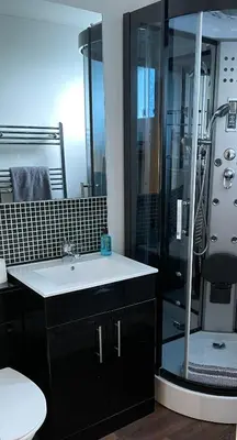 a bathroom with a glass shower and a sink at Kendall Lodge in Burwell