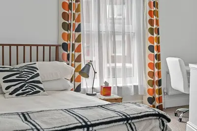 a bedroom with a bed and a lamp on a table at St John's Corner Cottage, Bury St. Edmunds in Bury Saint Edmunds