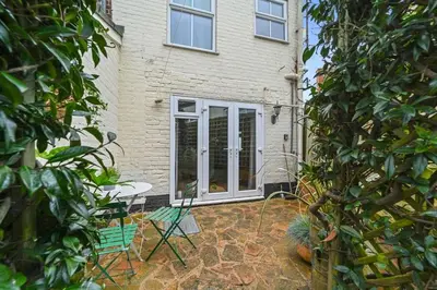 a house with a door and a green chair at St John's Corner Cottage, Bury St. Edmunds in Bury Saint Edmunds