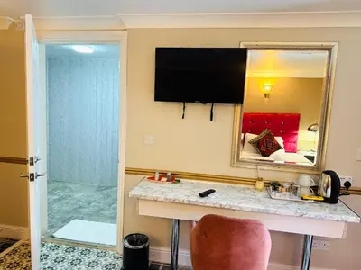 a hotel room with a vanity and a mirror at 4 Sisters Inn in Theydon Bois