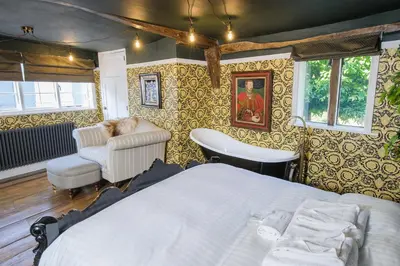 a bedroom with a bed and a chair at Luxury 3 Bed Manor House Hot Tub Cinema Room SkyTV in Saffron Walden