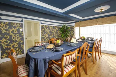 a dining room with a blue table and chairs at Luxury 3 Bed Manor House Hot Tub Cinema Room SkyTV in Saffron Walden