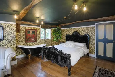 a bedroom with a large bed and a bath tub at Luxury 3 Bed Manor House Hot Tub Cinema Room SkyTV in Saffron Walden