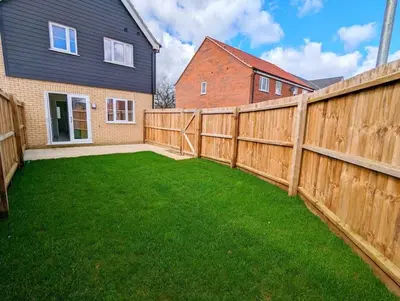 a backyard with a wooden fence and green grass at 3-Bed, Sleeps 5, 3 Bath, Parking, WiFi in Watton