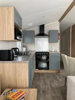 a kitchen with blue cabinets and a stove top oven at VerbZen Holiday Caravan at St Osyth Beach, Clacton-on-Sea by Verb Holidays in Saint Osyth
