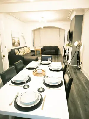 a table with plates and wine glasses on it in a living room at Spacious 3 Bedroom Home, Sleeps 7, Long-Stay & Contractor Friendly, Family & Professional Ready, Clark Property Estates in Southend-on-Sea