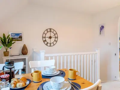 a dining room table with a clock on the wall at Bluebell Lodge in Longstowe