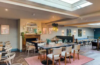 a dining room with tables and chairs and a fireplace at The George Hotel Colchester in Colchester