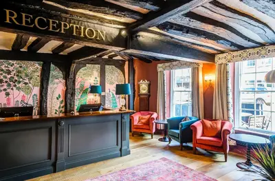 a room with chairs and a bar with a sign that reads reception at The George Hotel Colchester in Colchester