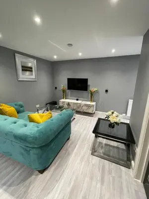 a living room with a green couch and a flat screen tv at Brook House Annex in Ipswich