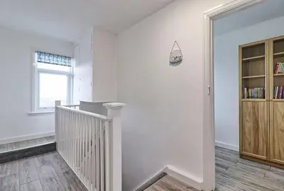a white room with a staircase and a book shelf at High view house, 3 bed flat, Number 41A in Walton-on-the-Naze