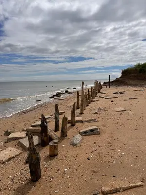 a beach with a row of wooden posts on it at Coastal Nest - Premium flat,3 Minutes to the Beach in Walton-on-the-Naze