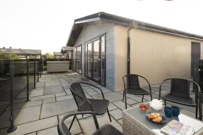 a patio with chairs and a table with food on it at Pebbles - Church Farm - Aldeburgh Coastal Cottages in Aldeburgh