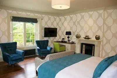 a bedroom with a bed and two chairs and a desk at The Oaksmere in Eye
