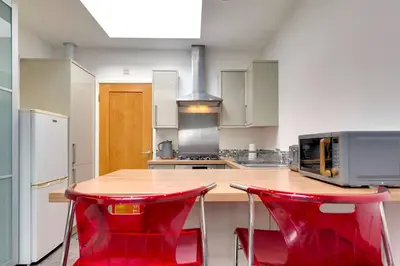 a kitchen with two red chairs at a wooden table at Pass the Keys Central Modern Cabin on Mill Road in Cambridge