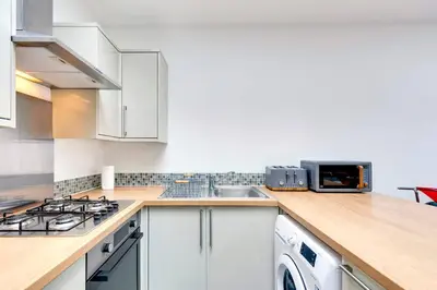 a kitchen with white cabinets and a sink at Pass the Keys Central Modern Cabin on Mill Road in Cambridge