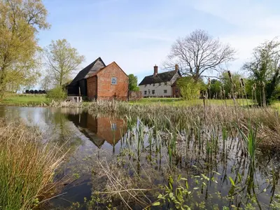 an old house and a pond in front of a house at Brook Farm in Harleston