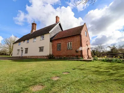 a large brick house with a grass field in front of it at Brook Farm in Harleston