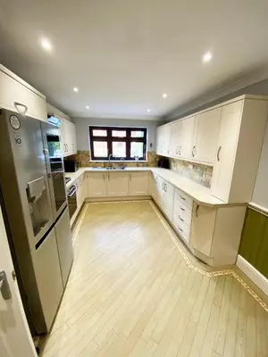 a large kitchen with white cabinets and a wooden floor at Emerson Park Mansion in Harold Wood