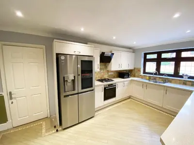 a kitchen with white cabinets and stainless steel appliances at Emerson Park Mansion in Harold Wood
