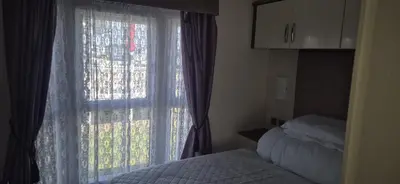 a room with a window with a bed and a window with a curtain at 3 Bedroom caravan St osyth beach holiday park with free WiFi and parking in Great Clacton