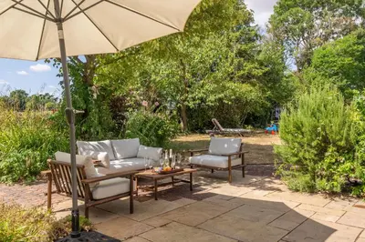 a patio with two chairs and an umbrella at Foxhole Cottage 8 in Stowmarket
