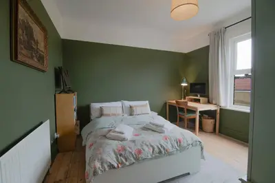 a green bedroom with a bed and a desk at Cosy Stylish house near Southend - Pass the Keys in Southend-on-Sea