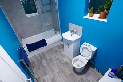 a blue bathroom with a toilet and a shower at 3 Bedroom home by Ipswich docks. in Ipswich