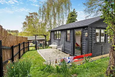 a black tiny house in a yard with a fence at 1 Bed in Chelmondiston oc-l29137 in Chelmondiston