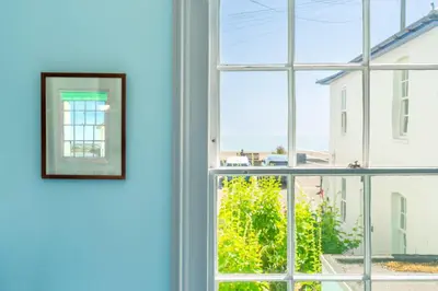 a picture hanging on a wall next to a window at Marine Cottage in Aldeburgh