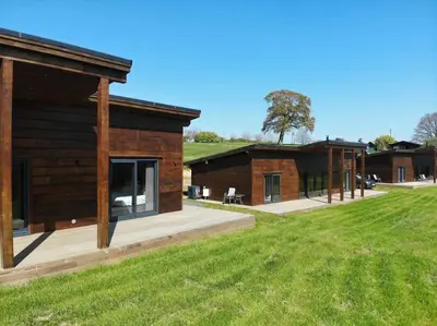 a log cabin with a grass field next to it at Meadow Valley Lodge 4 in Ipswich