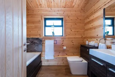 a wooden bathroom with a tub and a toilet and a sink at Meadow Valley Lodge 4 in Ipswich