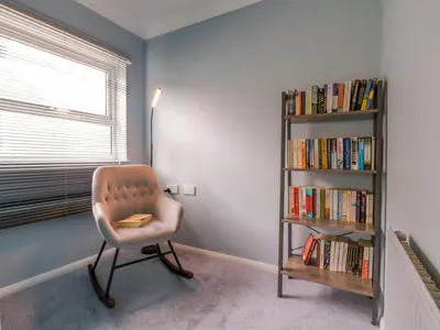 a room with a chair and a book shelf with books at The Annex in Colchester