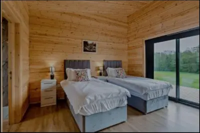 two beds in a room with wooden walls at Meadow Valley Lodge 1 in Ipswich