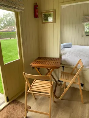a table and a chair in a room with a bed at Willow Shepherd Hut in West Row