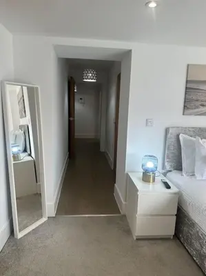 a bedroom with a bed and a hallway with a mirror at Relaxing 1 bedroom garden flat. in Brentwood