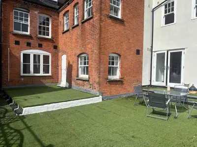 a patio with a table and chairs in front of a brick building at Relaxing 1 bedroom garden flat. in Brentwood