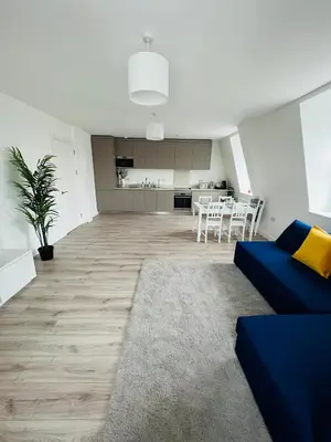 a living room with a blue couch and a kitchen at Stunning New Penthouse Apartment in Southend-on-Sea